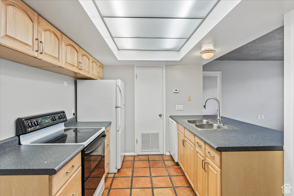 Kitchen with white appliances, sink, light brown cabinetry, and light tile floors