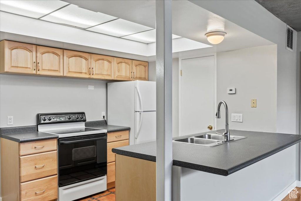 Kitchen featuring light brown cabinets, sink, white appliances, and light tile flooring