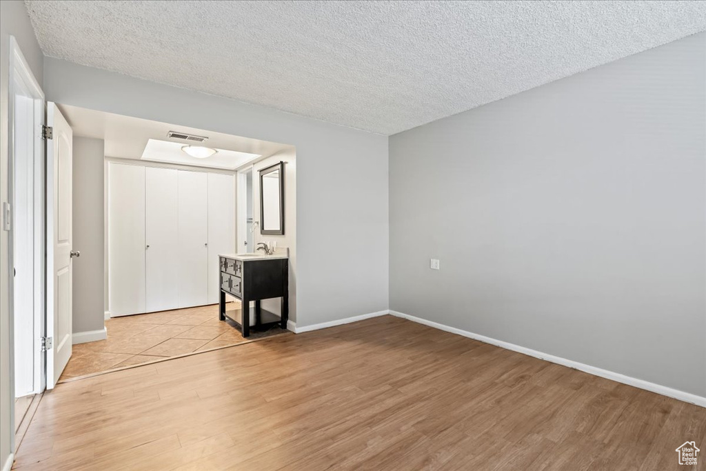 Unfurnished bedroom with sink, a textured ceiling, and light tile floors