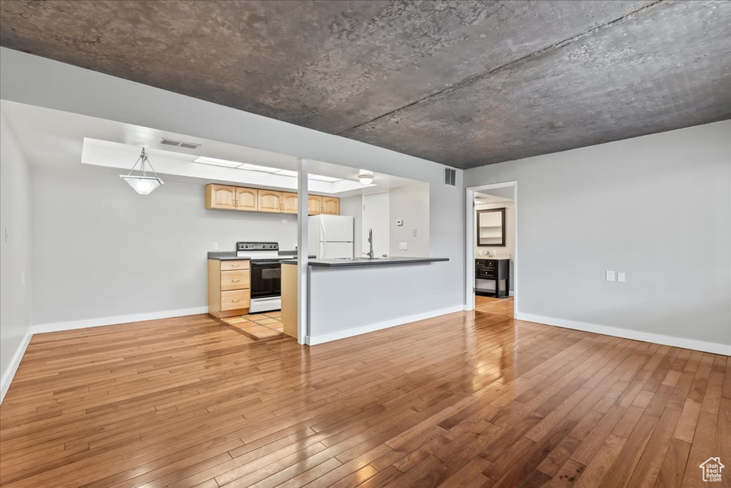 Interior space featuring light hardwood / wood-style flooring, kitchen peninsula, white appliances, and light brown cabinetry