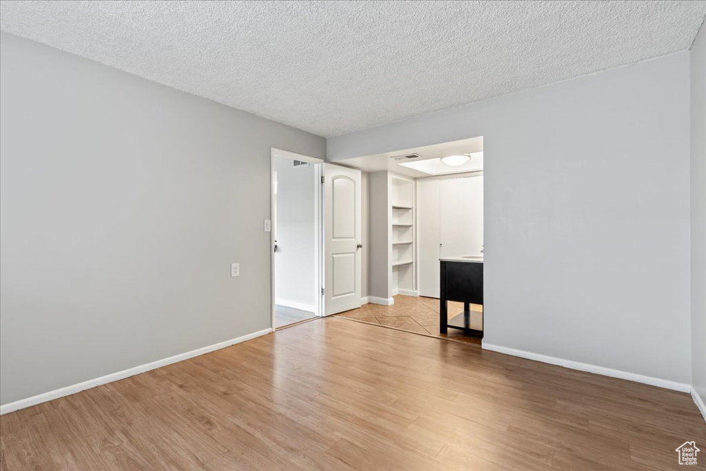 Unfurnished room with light hardwood / wood-style floors and a textured ceiling