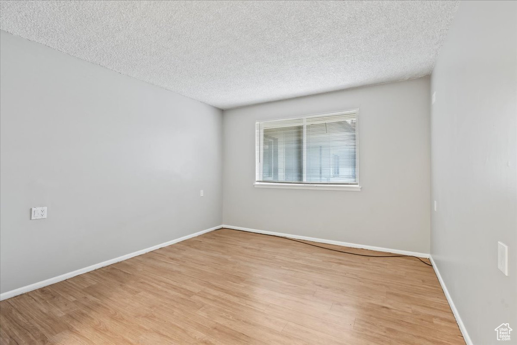 Unfurnished room with light hardwood / wood-style floors and a textured ceiling