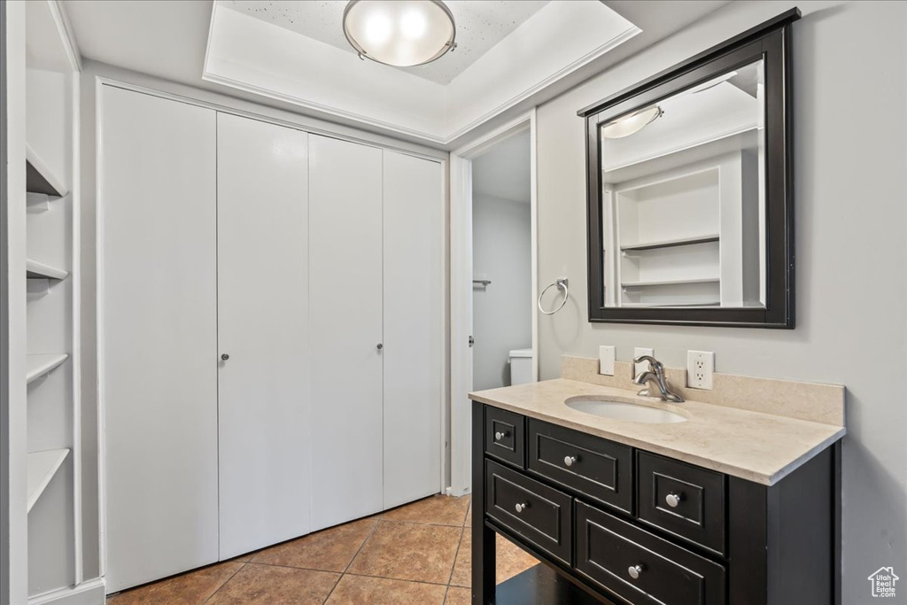 Bathroom featuring tile flooring, built in features, vanity, and a tray ceiling