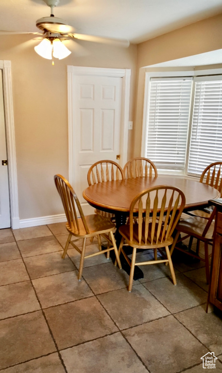 Tiled dining area featuring a healthy amount of sunlight and ceiling fan