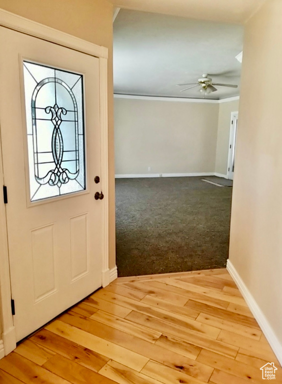 Entrance foyer featuring ceiling fan, light wood-type flooring, and crown molding