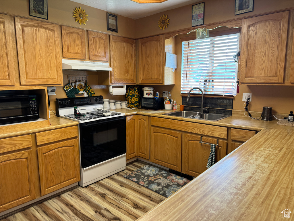 Kitchen featuring sink, white range with gas cooktop, and light hardwood / wood-style floors