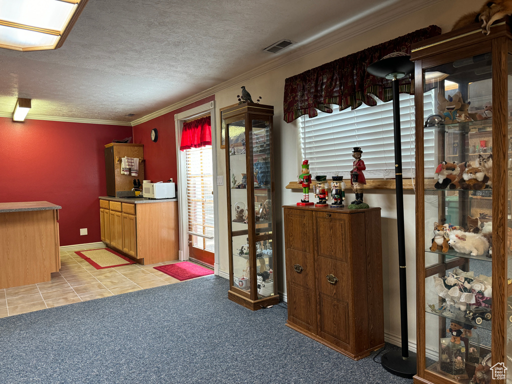 Kitchen featuring crown molding, a textured ceiling, and light tile flooring