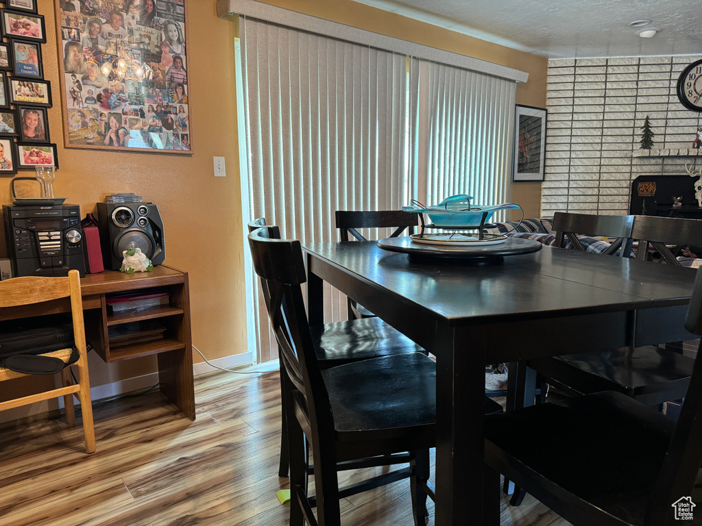 Dining room with hardwood / wood-style flooring, brick wall, and a textured ceiling