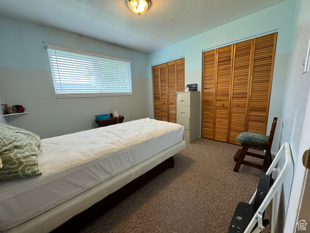 Bedroom featuring a textured ceiling, two closets, and carpet