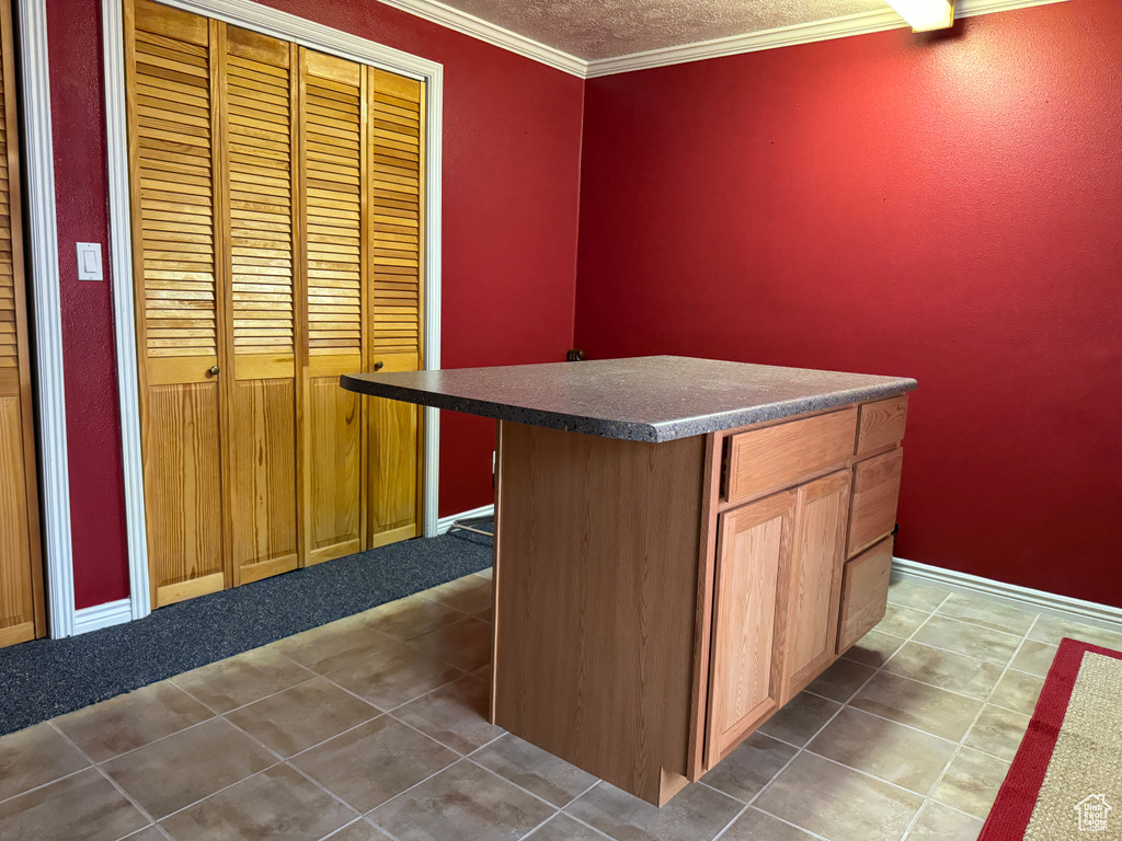 Kitchen with a center island, ornamental molding, and dark tile floors