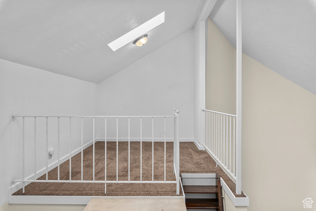 Stairway featuring vaulted ceiling with skylight and carpet floors