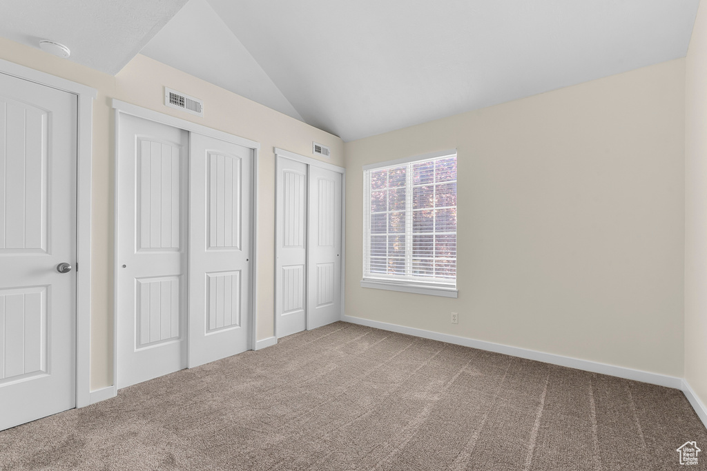 Unfurnished bedroom with carpet flooring and lofted ceiling