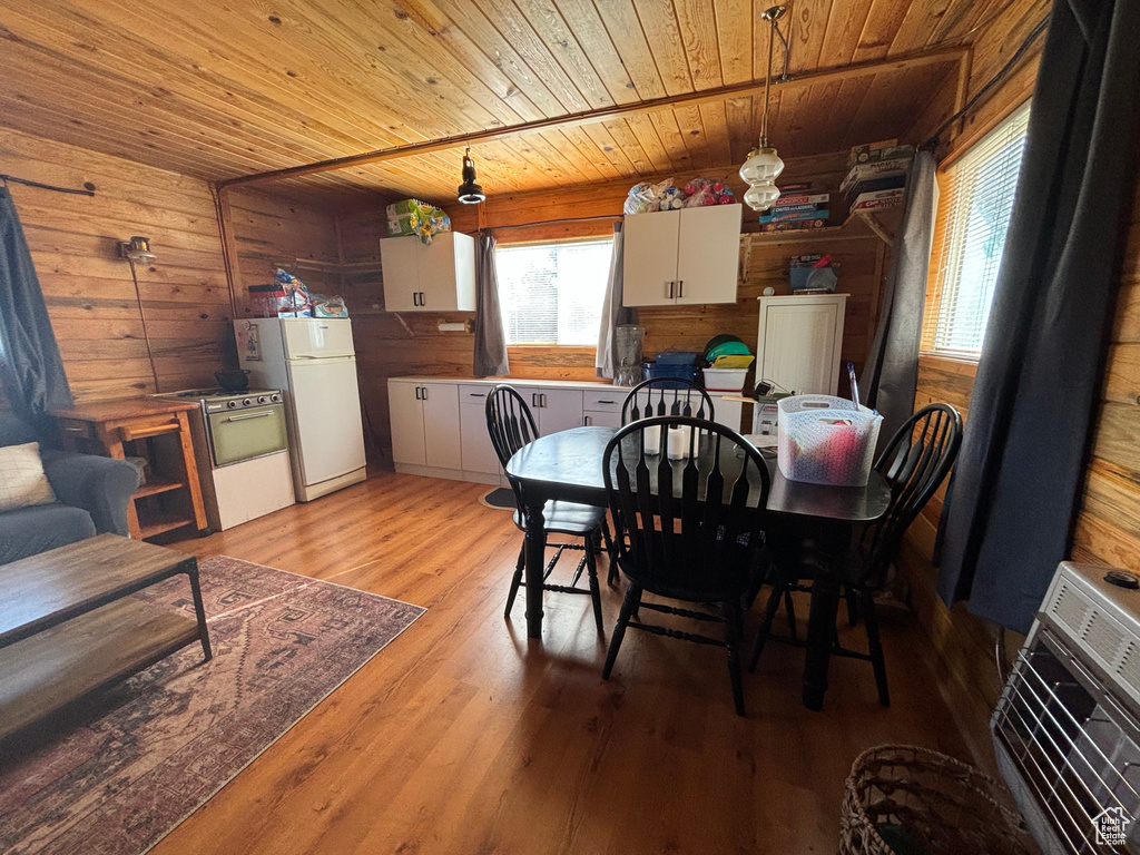 Dining room featuring light hardwood / wood-style floors, wood ceiling, and wood walls