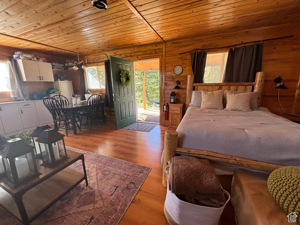 Bedroom featuring wood walls, access to exterior, light wood-type flooring, and wood ceiling