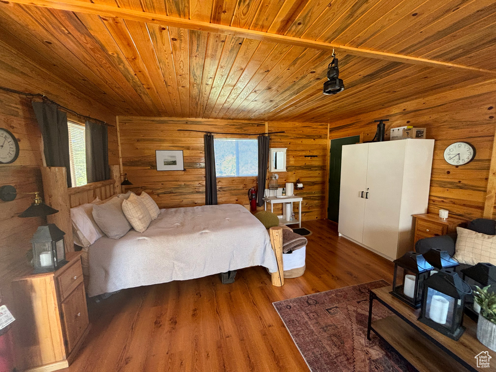 Bedroom with hardwood / wood-style floors, wooden walls, wood ceiling, and multiple windows