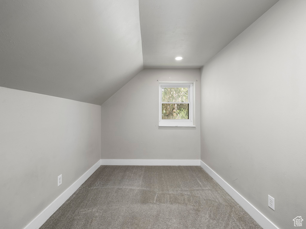 Additional living space featuring carpet floors and vaulted ceiling