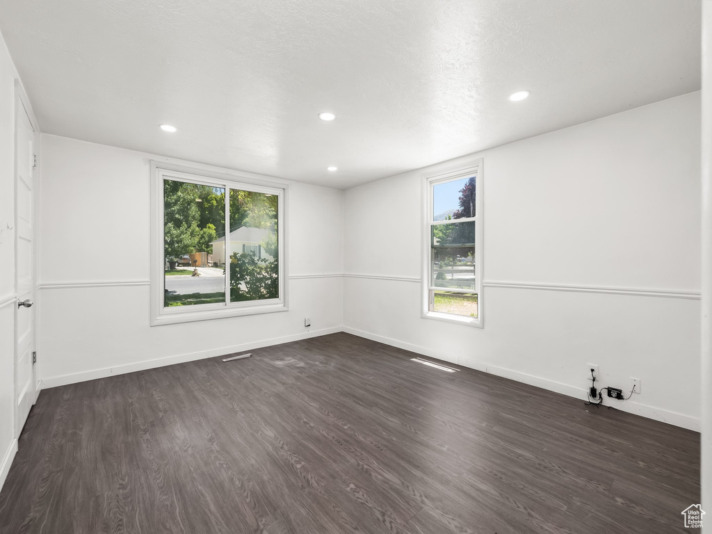 Spare room with a wealth of natural light and dark wood-type flooring