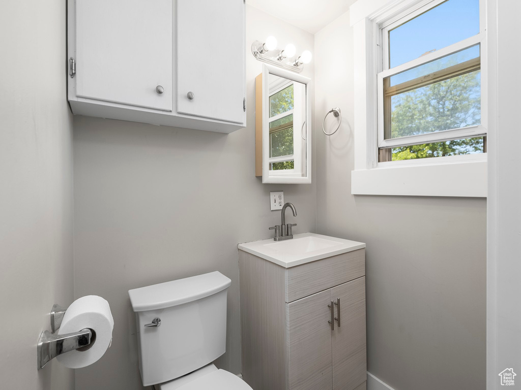 Bathroom featuring vanity with extensive cabinet space and toilet