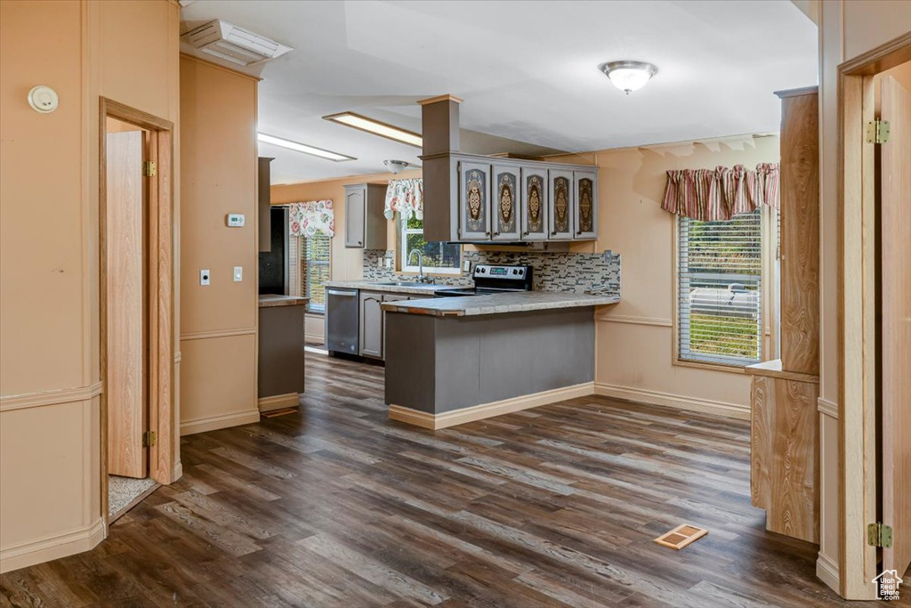 Kitchen with dark wood-type flooring, stainless steel dishwasher, electric range, kitchen peninsula, and backsplash