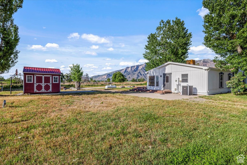 View of yard with a storage shed, a mountain view, and central AC unit