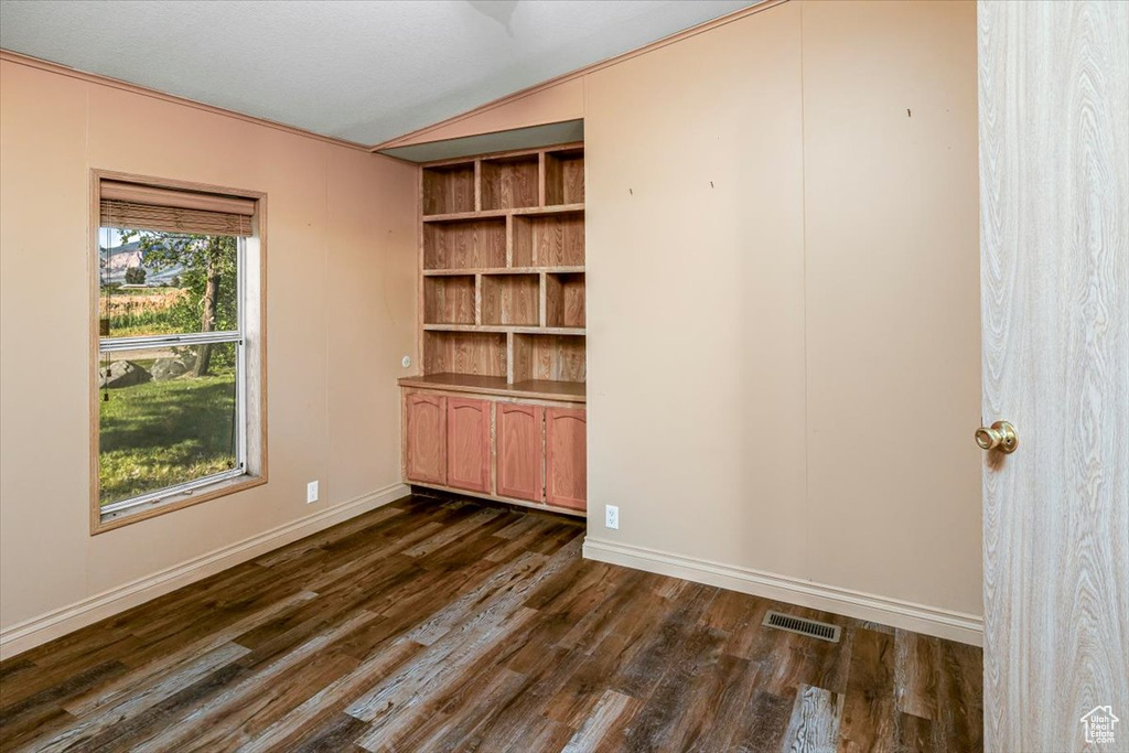 Spare room featuring ornamental molding, vaulted ceiling, and dark hardwood / wood-style flooring