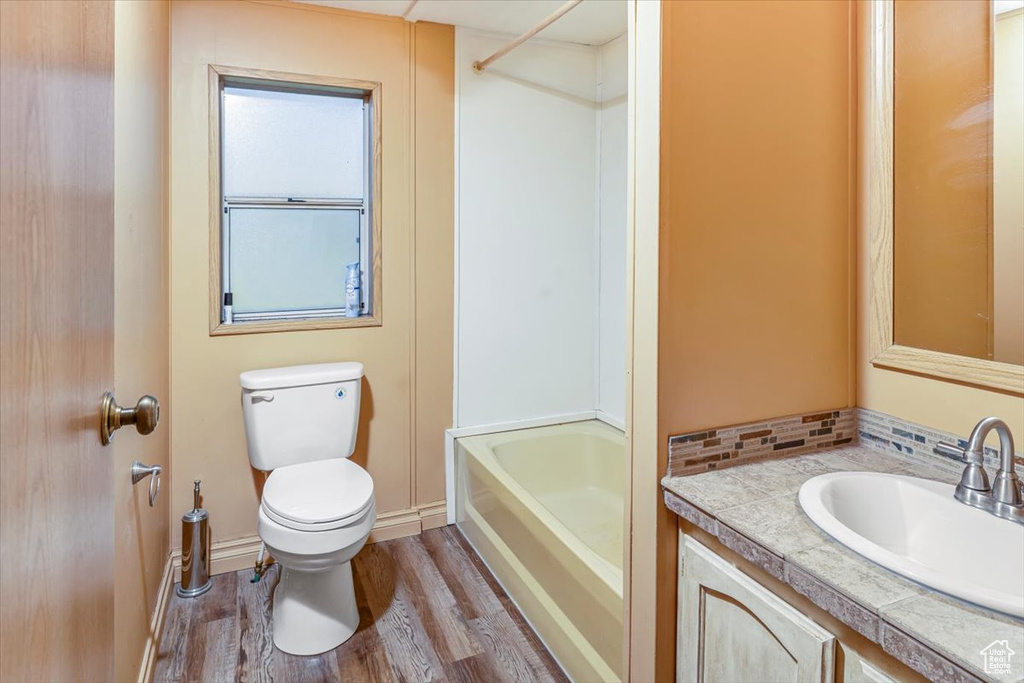 Full bathroom featuring hardwood / wood-style flooring,  shower combination, vanity, and toilet