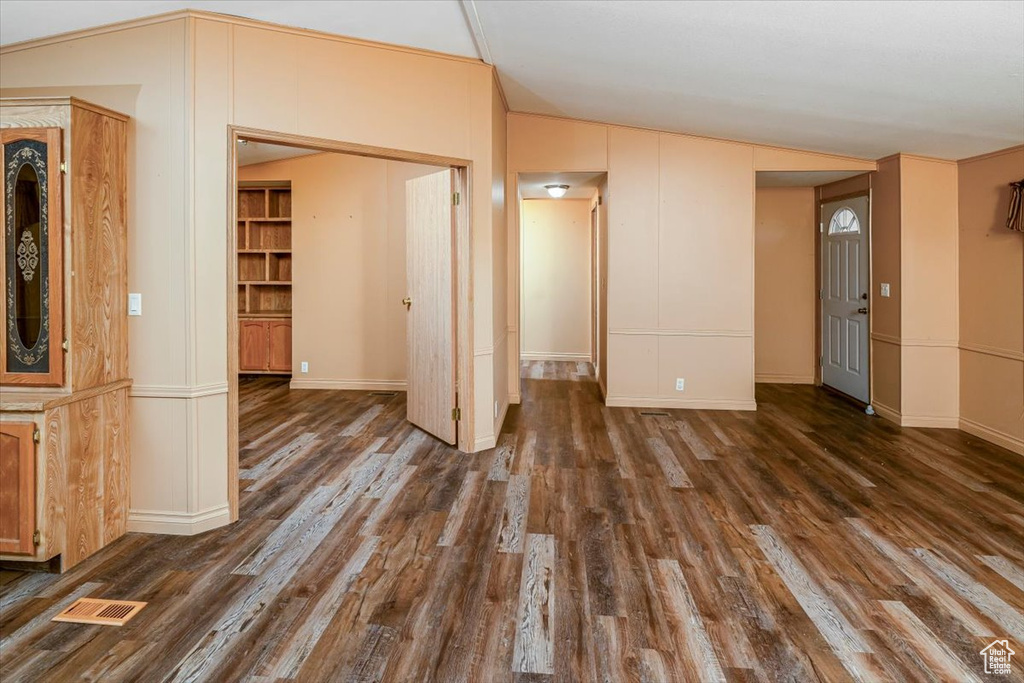 Unfurnished room with dark wood-type flooring and vaulted ceiling