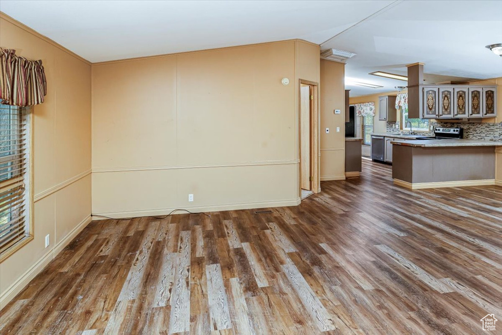 Unfurnished living room featuring sink, hardwood / wood-style flooring, and ornamental molding