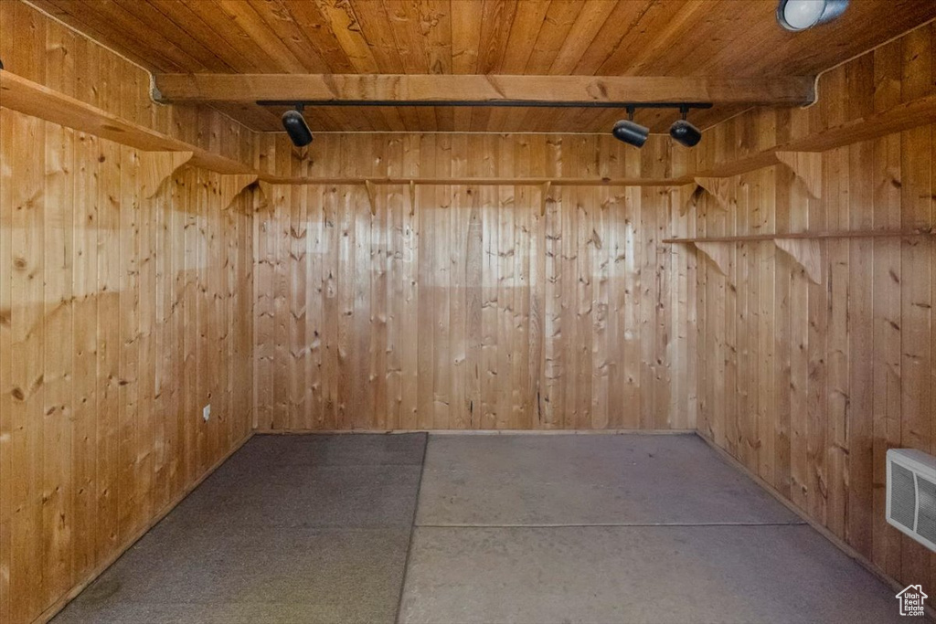 Empty room with beamed ceiling, wood ceiling, and wood walls