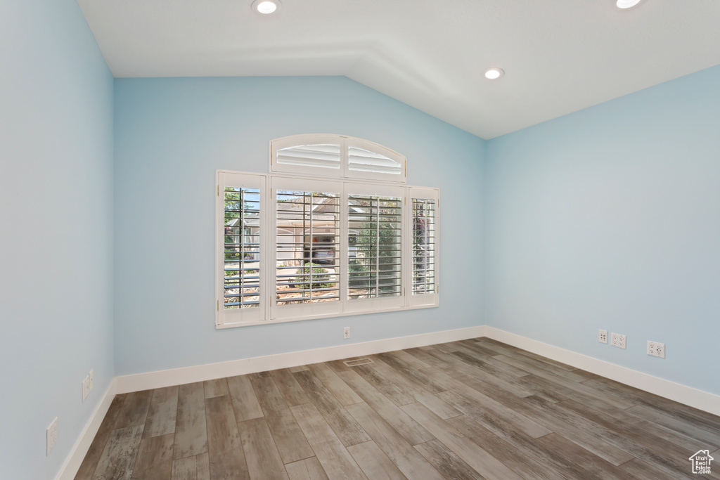 Empty room with vaulted ceiling and wood-type flooring