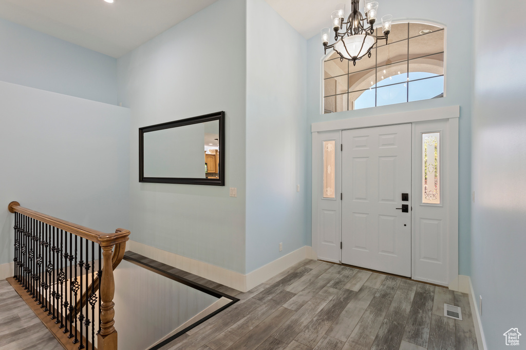 Foyer entrance featuring a chandelier, wood-type flooring, and a high ceiling