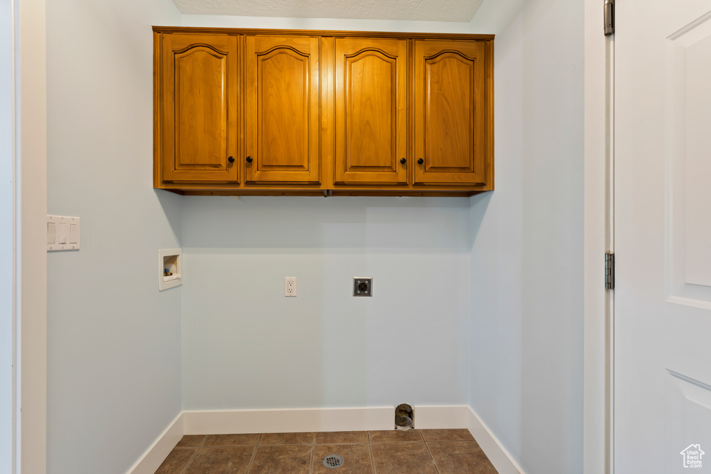 Laundry room with tile floors, hookup for a washing machine, electric dryer hookup, and cabinets