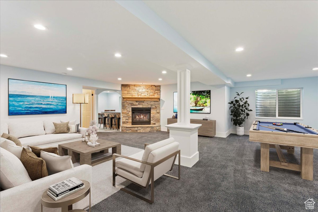 Living room featuring a stone fireplace, dark colored carpet, billiards, and decorative columns