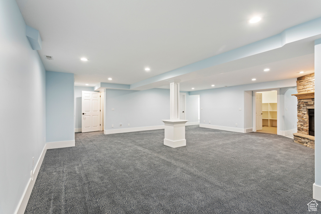 Basement with a stone fireplace and dark carpet