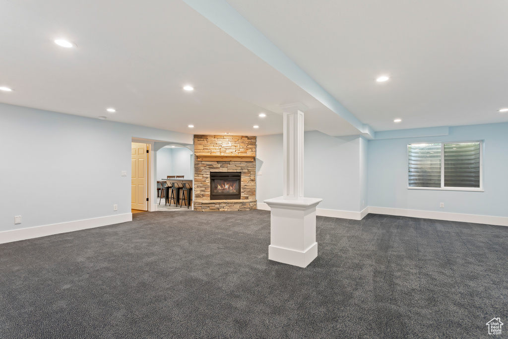 Unfurnished living room featuring a fireplace, dark carpet, and ornate columns