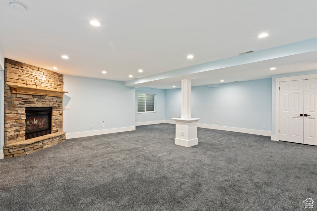 Basement featuring dark carpet and a stone fireplace