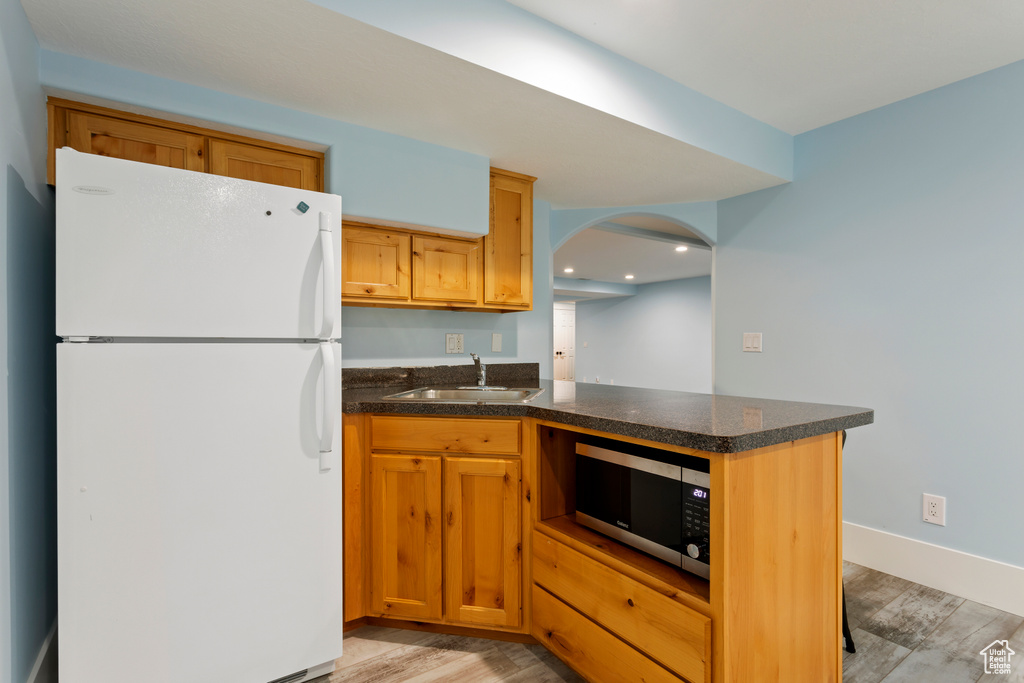 Kitchen with sink, white fridge, and light hardwood / wood-style floors