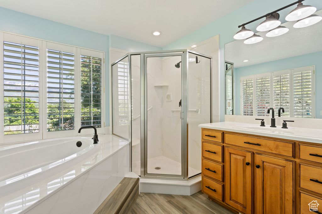 Bathroom featuring hardwood / wood-style floors, separate shower and tub, and vanity