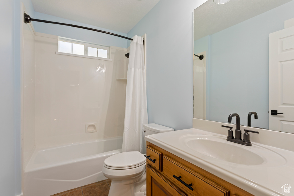 Full bathroom featuring shower / bath combo with shower curtain, vanity, toilet, and tile flooring