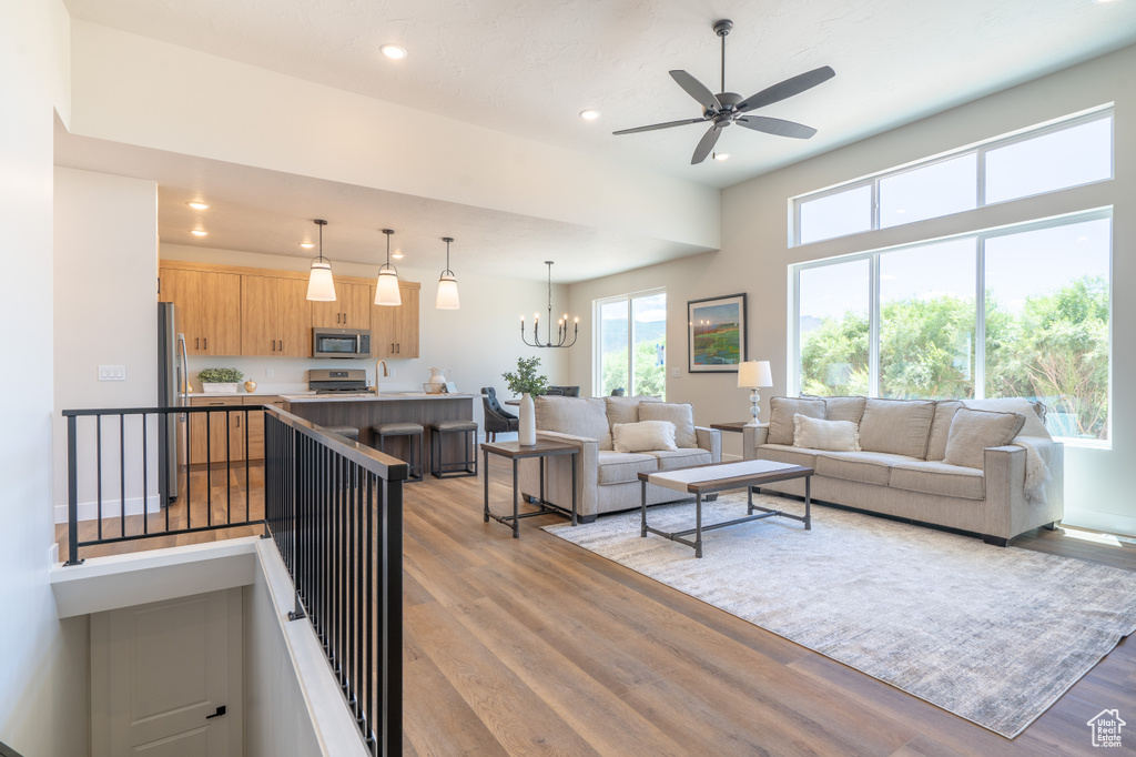 Living room with light hardwood / wood-style floors and ceiling fan with notable chandelier