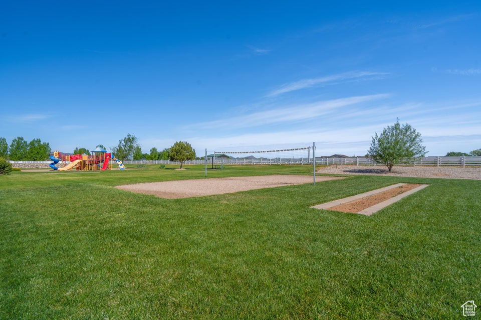 Exterior space with volleyball court, a playground, and a lawn