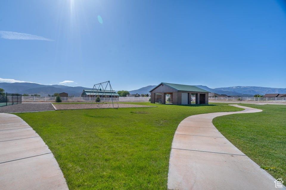 Surrounding community with a mountain view and a lawn