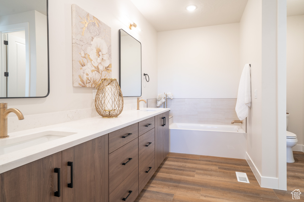 Bathroom with hardwood / wood-style floors, oversized vanity, double sink, and a bath