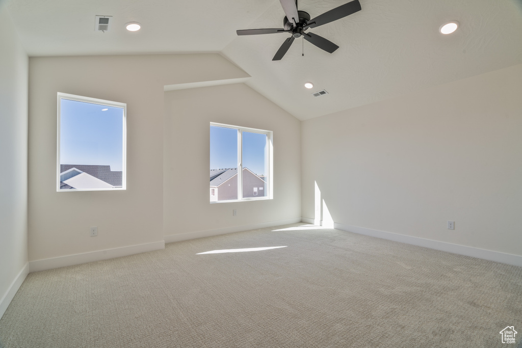 Carpeted empty room featuring ceiling fan and vaulted ceiling