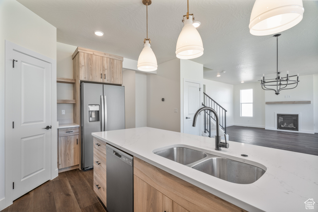 Kitchen with hanging light fixtures, dark hardwood / wood-style flooring, appliances with stainless steel finishes, light brown cabinetry, and sink