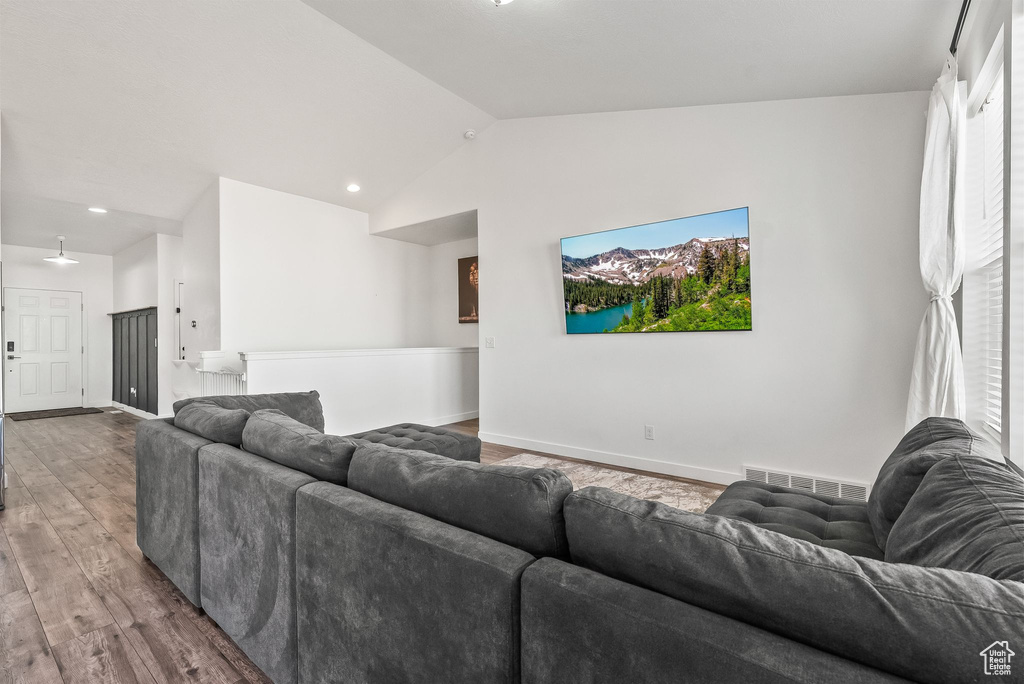 Living room featuring wood-type flooring, vaulted ceiling, and plenty of natural light