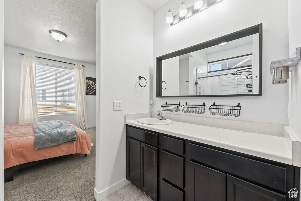 Bathroom featuring walk in shower, vanity, a textured ceiling, and a wealth of natural light