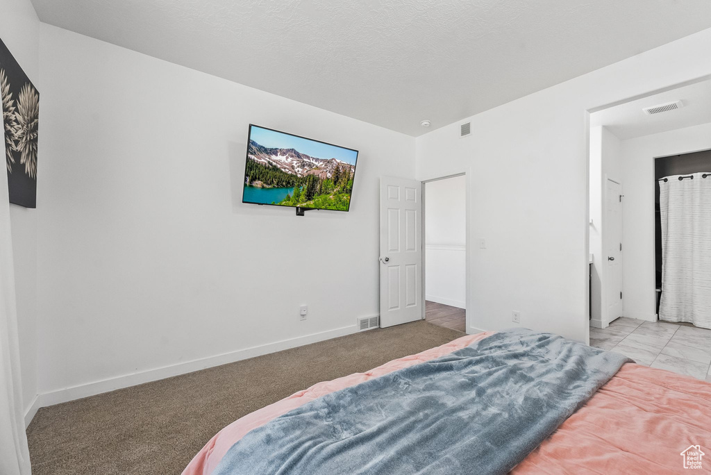 Bedroom featuring a textured ceiling and light carpet