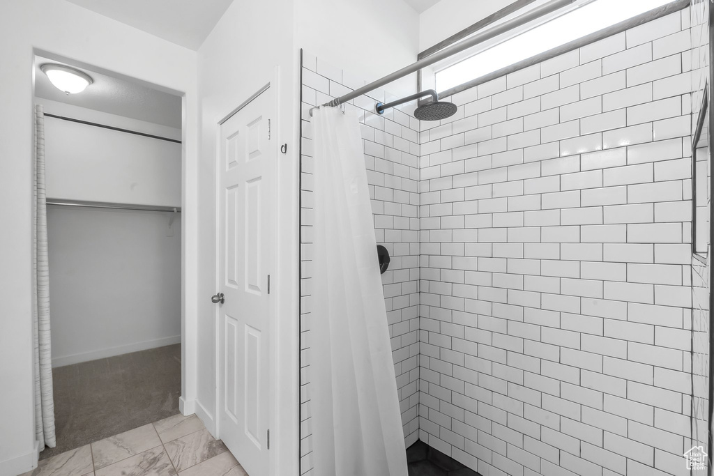 Bathroom with a shower with curtain and tile patterned floors