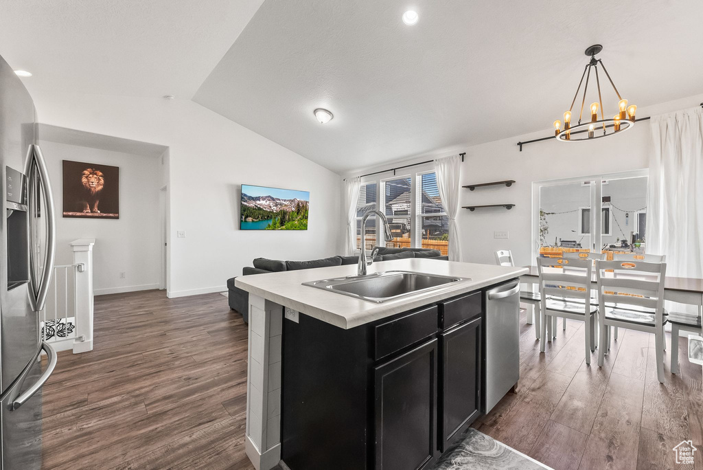 Kitchen featuring appliances with stainless steel finishes, hanging light fixtures, an island with sink, dark hardwood / wood-style floors, and sink